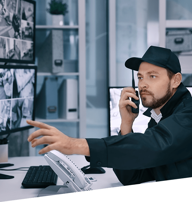 a security personnel holding a handheld radio while pointing at a monitor