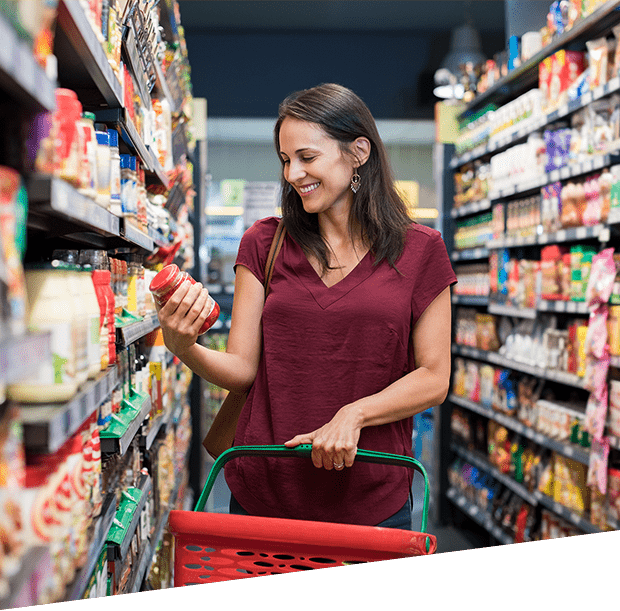 a smiling woman holding a jar in a supermarket