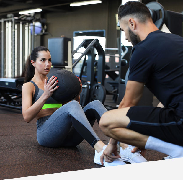 Trainer helping young woman to do abdominal exercis
