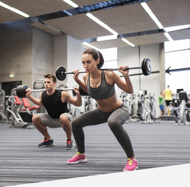 Young man and woman training with barbell in gym